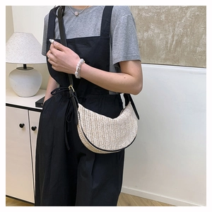 Dettaglio borsa a tracolla beige intrecciata con spalline in pelle nera e fibbie dorate