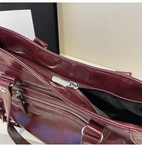 Detail of burgundy waxed leather tote showing silver zipper closure and interior lining