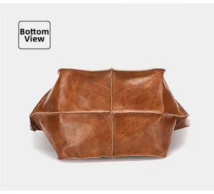Detailed bottom view of the brown leather tote bag with cross stitching and vintage texture
