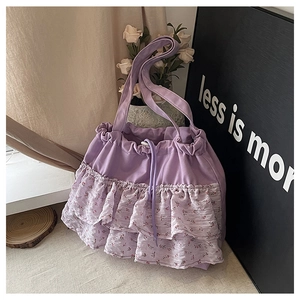Detalle del bolso tote lila con volantes florales, cierre de cordón y correa ancha