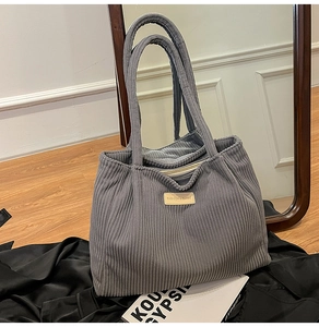 Detail of grey corduroy tote bag with vertical texture and fashion leather label