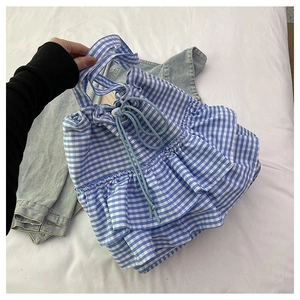Detail view of blue gingham tote bag with ruffles and drawstring closure on white fabric