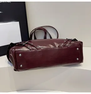 Close-up of dark burgundy tote base with silver protective metal studs and rivet details