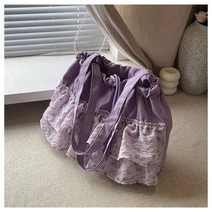 Detalle del bolso tote de lona morada con volantes florales y cierre de cordón