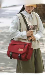 Detail of red messenger bag with flap closure and adjustable strap on a male model