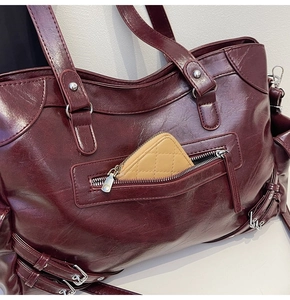 Detail shot of a dark burgundy tote bag featuring front zip pocket and silver metal hardware