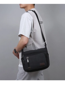 Detailed side view of a black canvas messenger bag on a male model for casual use