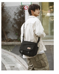Detail of black tactical messenger bag with flap closure and adjustable shoulder strap