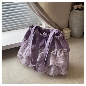 Detalle de bolso tote de flores moradas con bordes volantes y cierre de cordón