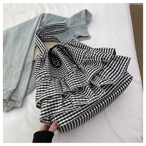Detail of gingham tote bag with layered ruffles and drawstring on fabric background
