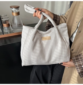 Close-up of corduroy tote bag featuring a leather logo patch and textured fabric surface