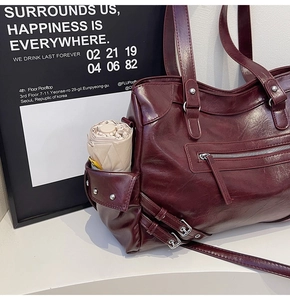 Detail of burgundy tote bag side pocket holding a small umbrella with silver stud accents