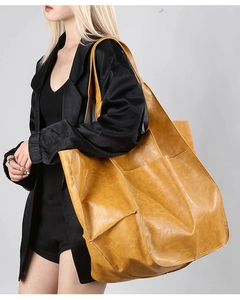 Detailed view of a vintage yellow leather tote bag with a large front pocket and spacious interior
