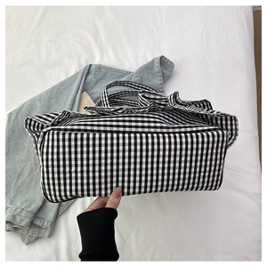 Detail view of large checkered tote bag with wavy ruffle edges and canvas texture