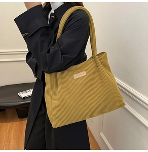 Detail of the mustard yellow corduroy tote bag featuring a leather fashion label and texture