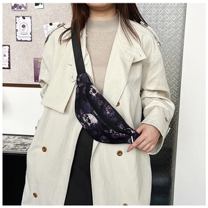 Détail d'un sac de poitrine gothique avec fleurs violettes et crâne sur un manteau beige