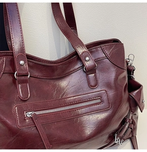 Close-up of a burgundy vintage tote bag featuring silver rivet hardware and oil leather texture