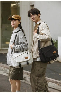 Detailed view of canvas messenger bags in black and beige with buckle closures
