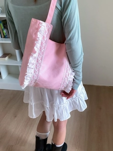 Pink canvas tote bag with white lace trim and ruffled details on female model shoulder