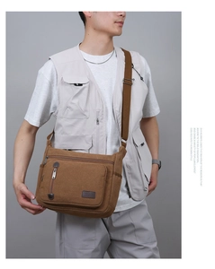 Close-up of a brown canvas messenger bag with a large zip pocket and leather patch detail