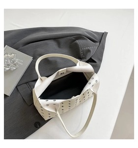 Detail of white hollowed rivet bag showing magnetic closure and spacious black lining