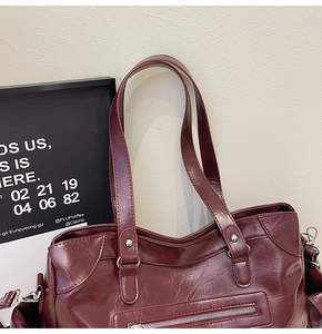 Detail of burgundy wax leather tote bag with silver rivets and metallic zippers