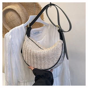Dettaglio della borsa in paglia intrecciata beige con tracolla in pelle e fibbia oro