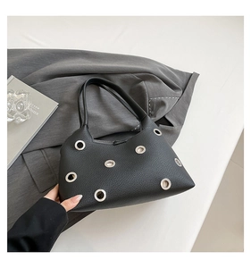 Detail view of black lychee grain leather underarm bag with silver metal eyelet accents