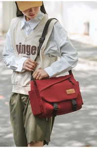 Detail of red messenger bag showing flap closure with buckles and durable nylon texture