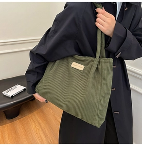 Detail view of dark green corduroy tote bag featuring a leather fashion logo patch