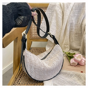 Dettaglio della borsa hobo intrecciata beige con tracolla in pelle nera e oro