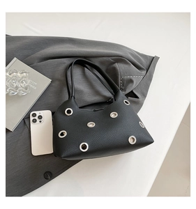 Detailed macro view of black lychee grain leather handbag with silver metal eyelet hardware