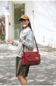 Detail of red canvas messenger bag featuring buckle closure and adjustable strap