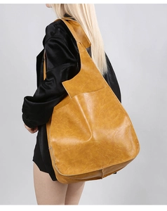 Detail of soft mustard yellow leather hobo bag with wide shoulder strap shown on model