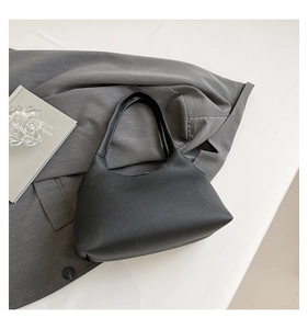 Close-up of black lychee grain leather handbag with minimalist half-moon silhouette