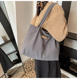 Detail of grey corduroy tote bag featuring a brown leather label on soft fabric