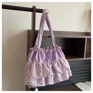Detalle de bolso tote morado con volantes florales y cierre de cordón en soporte