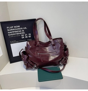 Detail of burgundy large tote bag showing metal buckles and smooth synthetic leather