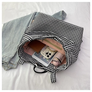 Interior view of black and white checkered tote bag showing pink lining and zipper pocket