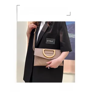 Detail view of beige leather clutch with gold metal buckle and crocodile embossing texture