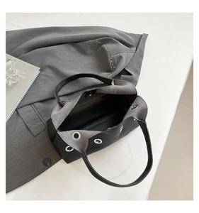 Detail of black leather underarm bag with metal eyelets and textured lychee grain finish