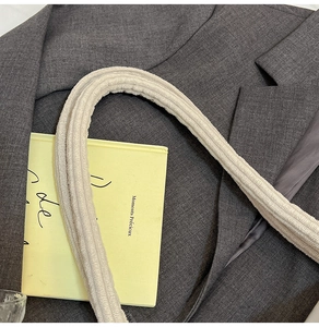 Close-up of cream ribbed texture canvas strap against a dark gray blazer fabric