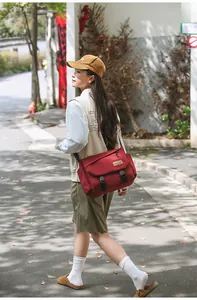 Close-up of a large red nylon messenger bag with black buckles and side storage pockets