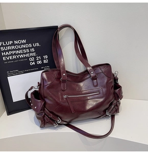Detail view of burgundy leather tote bag with rivets and functional side pockets