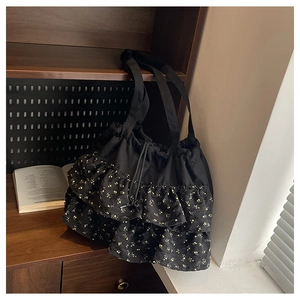 Detalle de volantes florales en bolso tote de gasa negra con cierre de cordón
