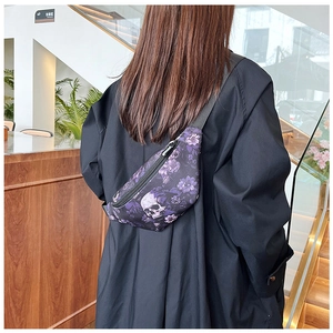 Détail d'un sac de poitrine punk avec imprimé tête de mort et fleurs porté dans le dos