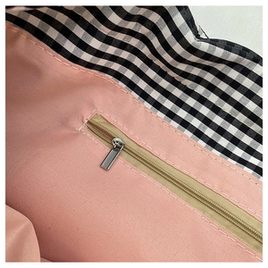 Detail shot of the pink fabric lining and silver zipper pocket inside the floral tote bag
