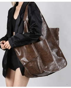 Detail view of large dark brown leather tote bag with vintage texture and front pockets