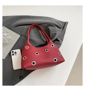 Close-up of red lychee textured handbag featuring large silver metal eyelets and handles