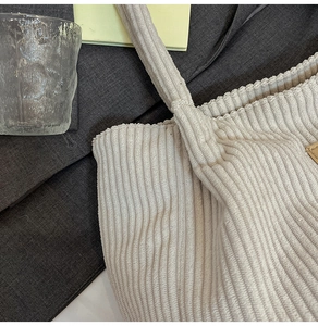 Detailed close-up of corduroy fabric texture and leather tag on beige tote bag